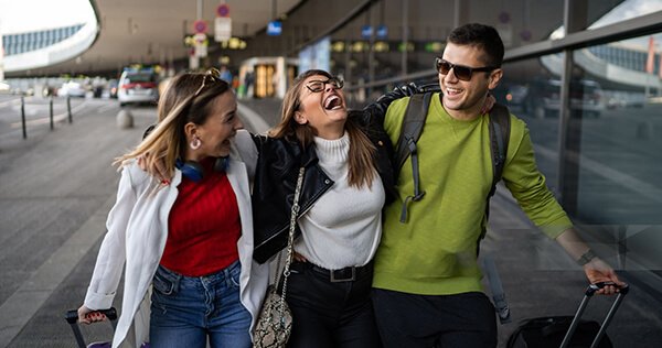 Happy friends arriving at the airport with luggage — seamless pickup and transport by NaviKorea